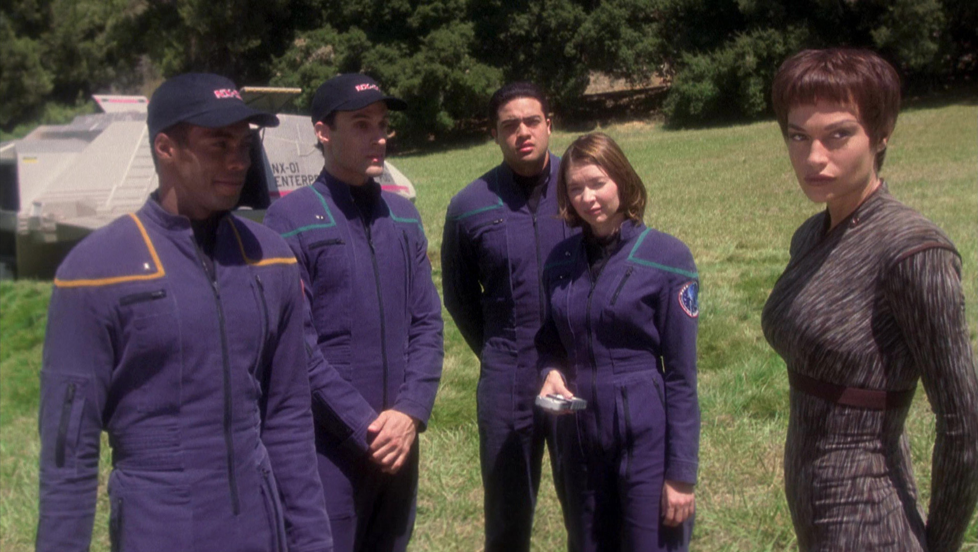 Several Starfleet officers stand on a planet in their uniforms.